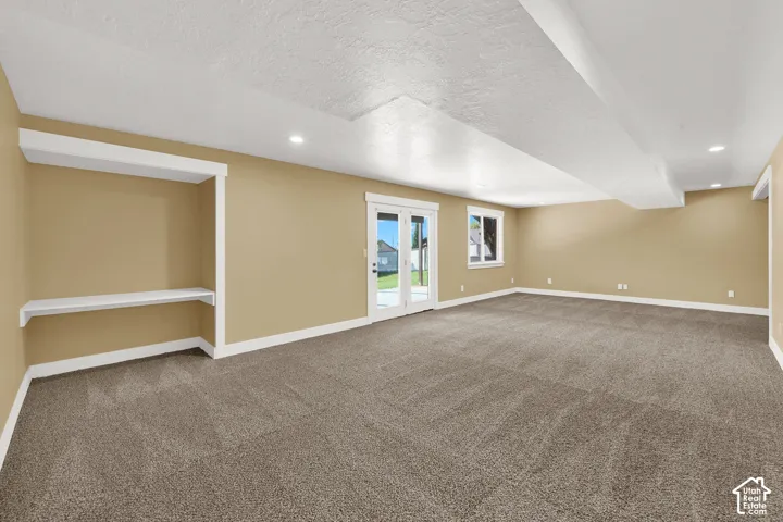 Spacious room featuring neutral carpeting, built-in recessed shelving, double glass-pane doors, and recessed lighting