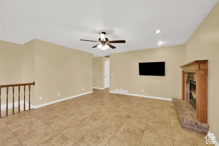 Living area featuring tile flooring, a brick fireplace with a wood mantel, a ceiling fan with integrated lighting, and recessed ceiling lights