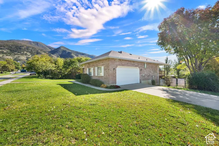 Brick exterior garage featuring a white sectional door, concrete driveway, and mountain scenery