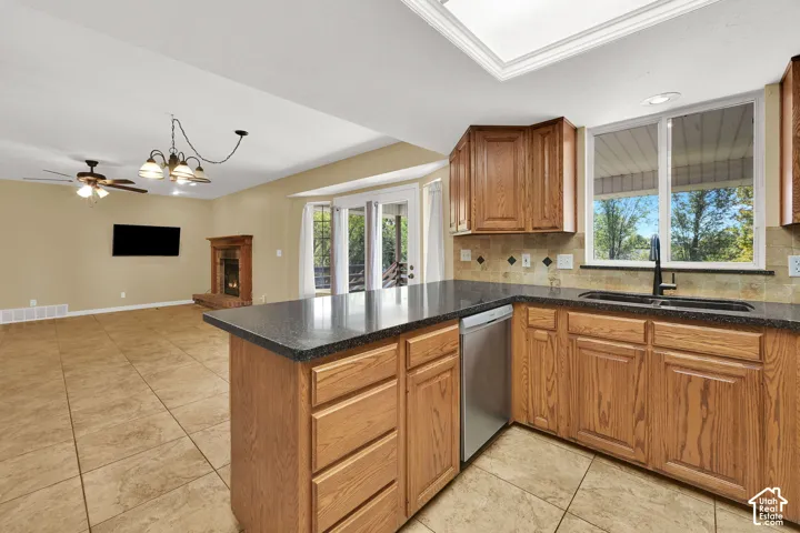 Kitchen featuring shaker-style wood cabinetry, dark stone countertops, tile backsplash, and tile flooring, paired with a fireplace featuring a traditional mantle