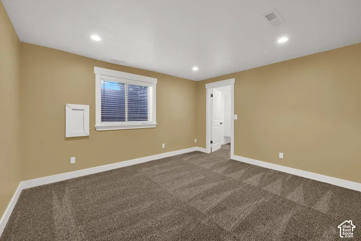 Neutral-toned interior featuring wall-to-wall carpeting, recessed ceiling lighting, a slider window with integrated blinds, and white-trim door framing