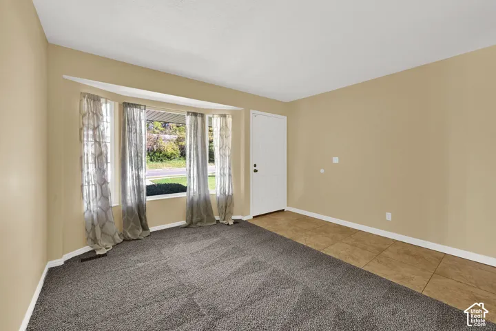 Large bay window, neutral wall paint, tile entry flooring, wall-to-wall carpeting, and solid-core entry door