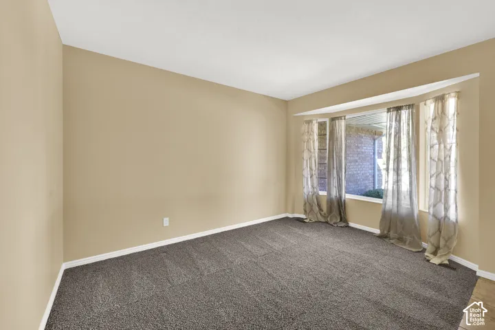 Neutral-toned interior space featuring wall-to-wall carpeting and a multi-paneled bay window