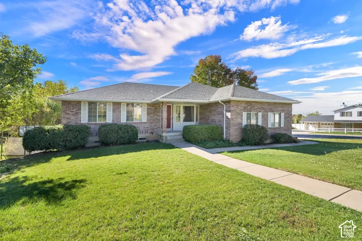 Brick exterior residence featuring a hip roof, white-framed windows, and a concrete walkway