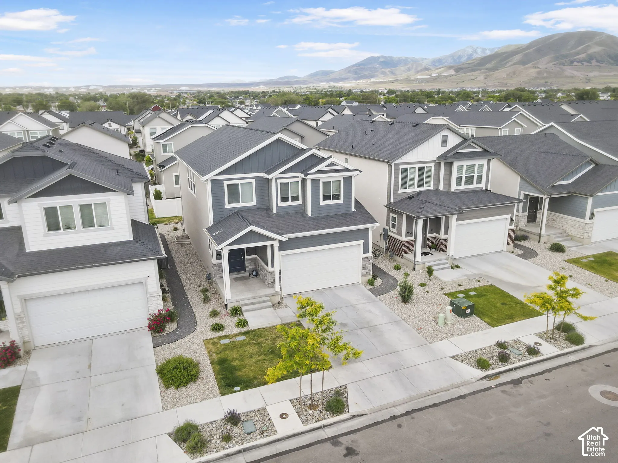 Two-story residence with a two-car garage, covered porch entry, and a gravel and grass yard