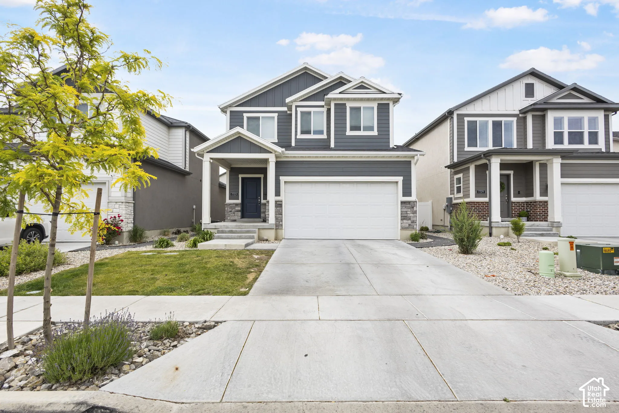 Two-story exterior with dark gray siding, white trim, stone accents, a covered front porch, and an attached two-car garage
