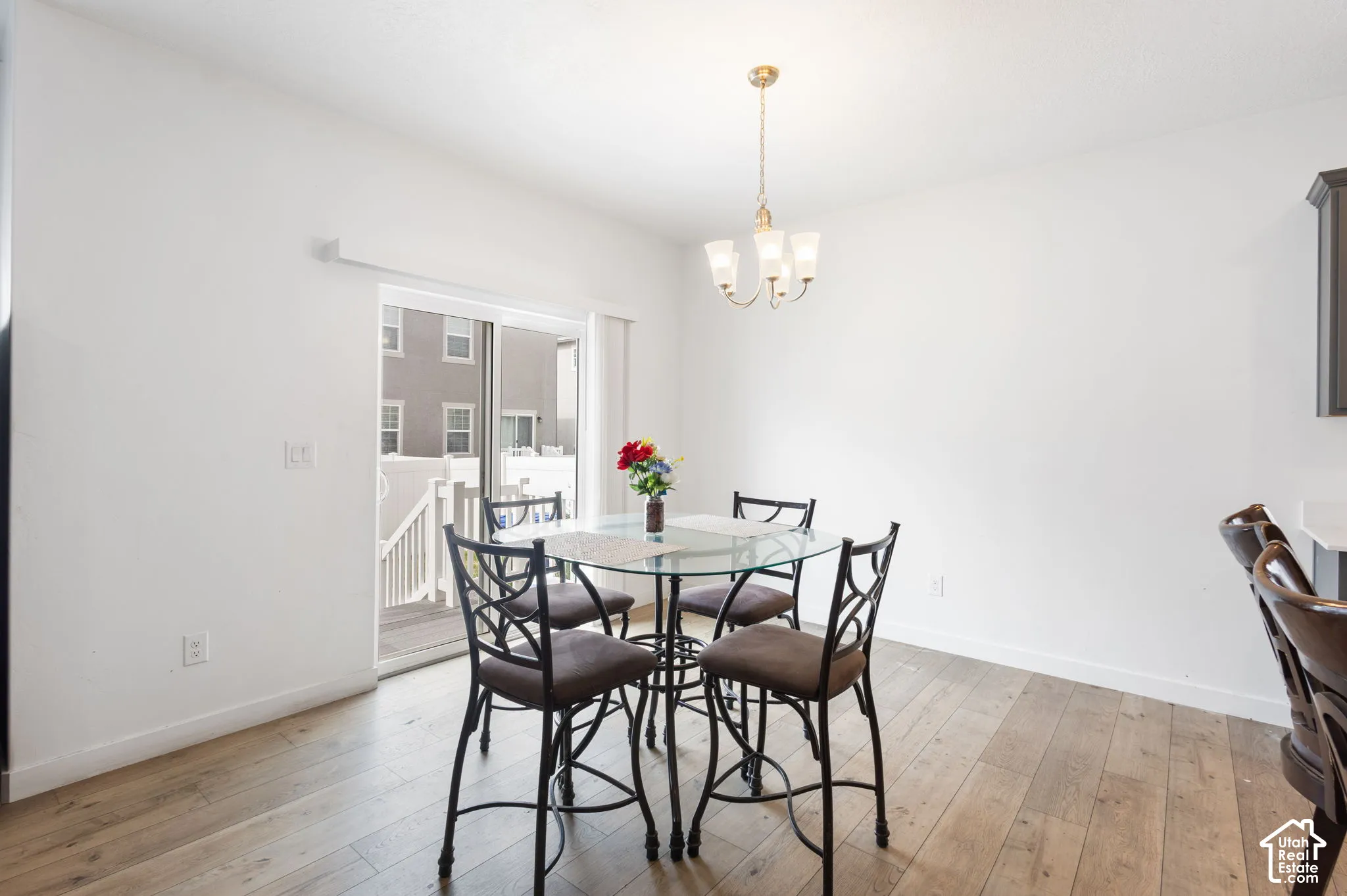 Wood-finish flooring, white walls, overhead chandelier, and sliding glass door