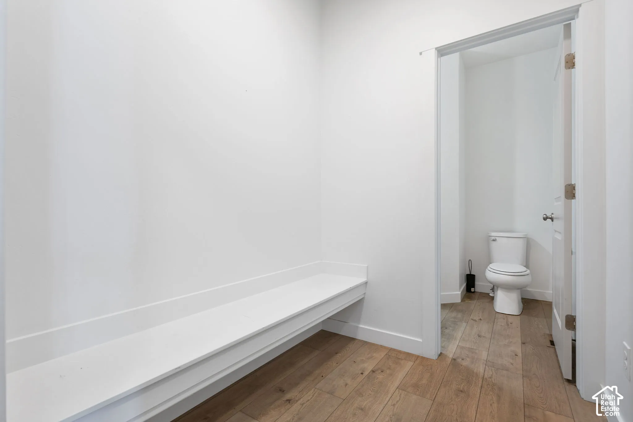 Built-in bench seating with a matte white finish, wood-finish flooring, and white walls