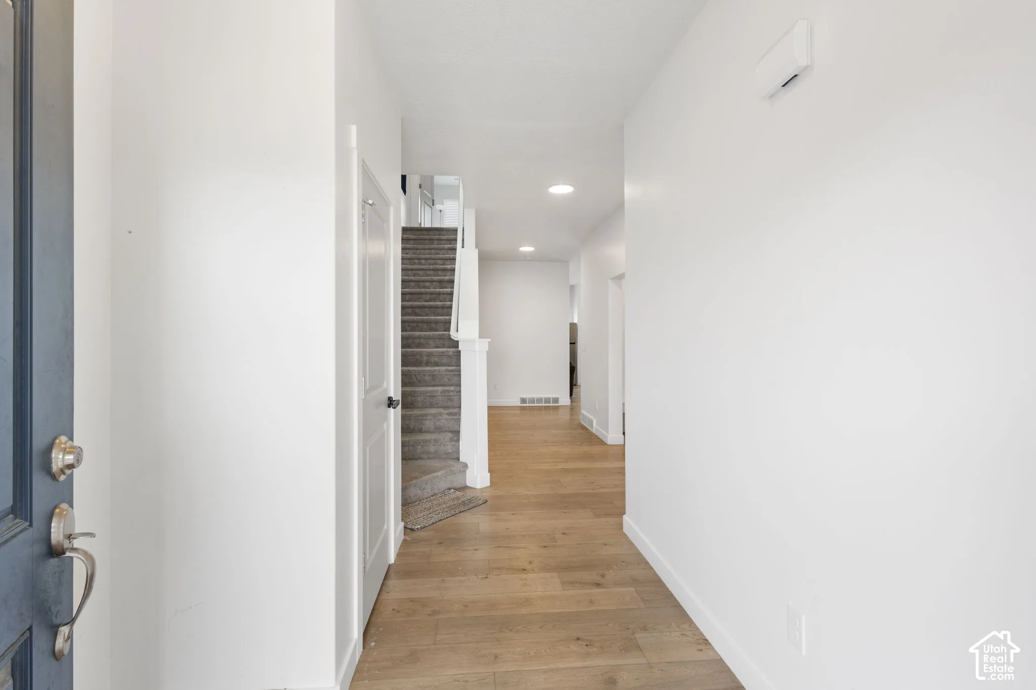 Entryway featuring wood-finish flooring, white walls, recessed lighting, and a staircase with carpeted treads