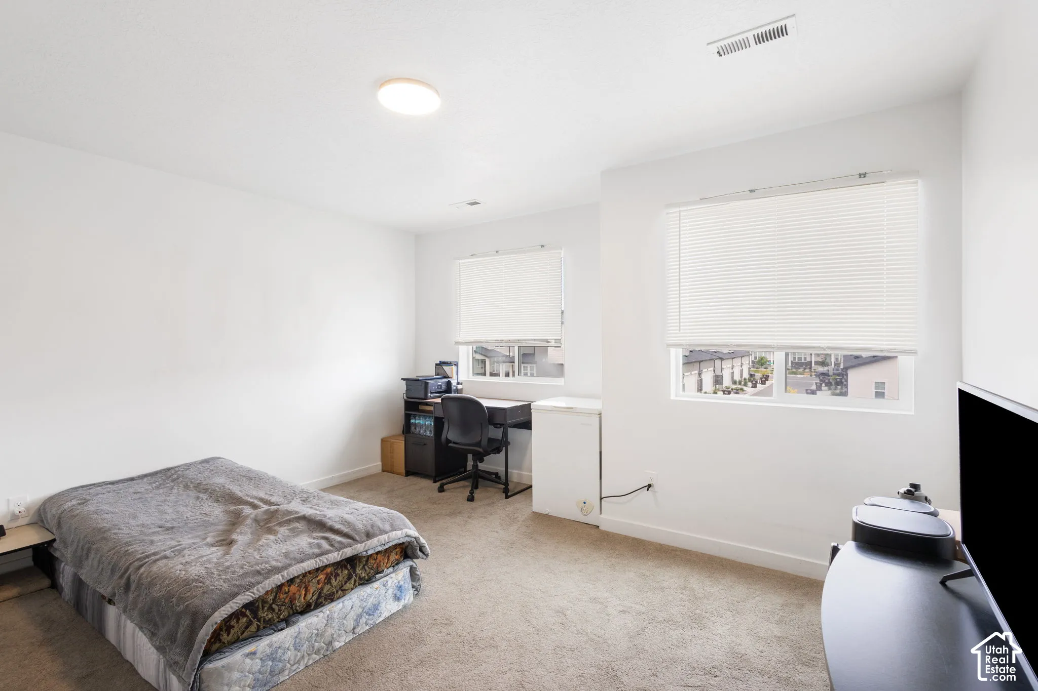 Recessed ceiling light fixture, two windows with horizontal blinds, and carpeted flooring