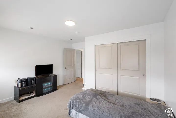 Recessed lighting, light-toned carpeting, white walls, and a closet with sliding panel doors