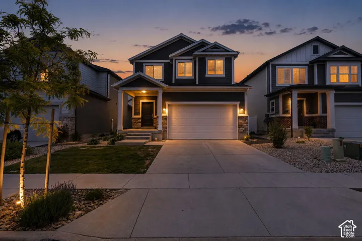Two-story residence featuring a stone and siding exterior, an attached two-car garage, and a covered front porch