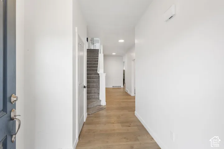Entryway featuring wood-finish flooring, white walls, recessed lighting, and a staircase with carpeted treads