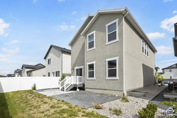 Two-story stucco exterior with white trim accents and a white vinyl fence