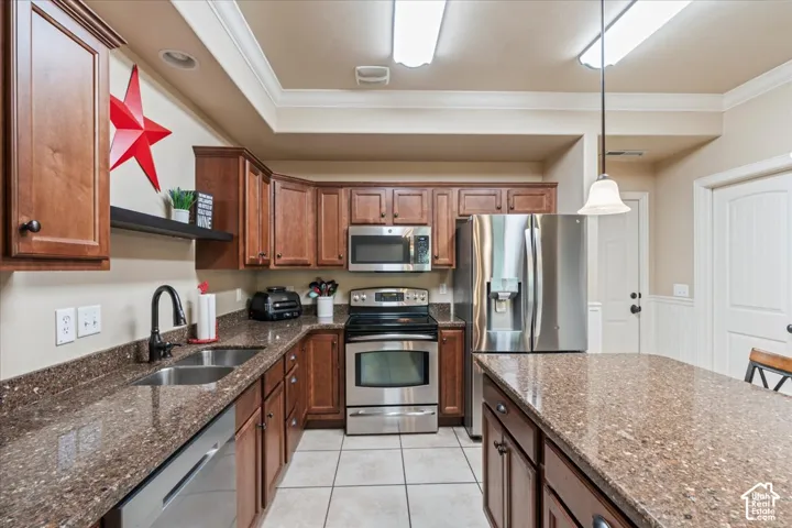 Kitchen featuring wood cabinetry, stainless steel appliances, speckled stone countertops, and tile flooring