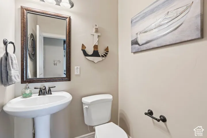 Pedestal sink with dark bronze faucet, framed mirror, and coordinating wall-mounted light fixture