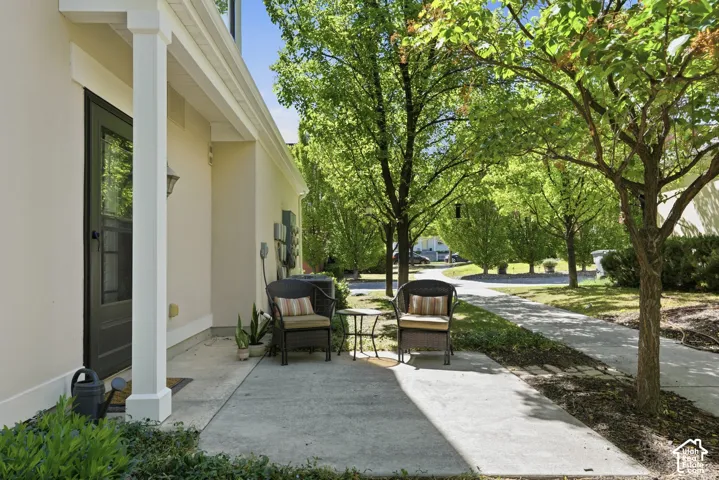 Entryway with a white column, dark-framed storm door, and covered concrete patio