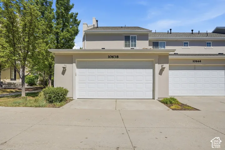 Stucco exterior with two-car garage, concrete driveway, and second-story windows