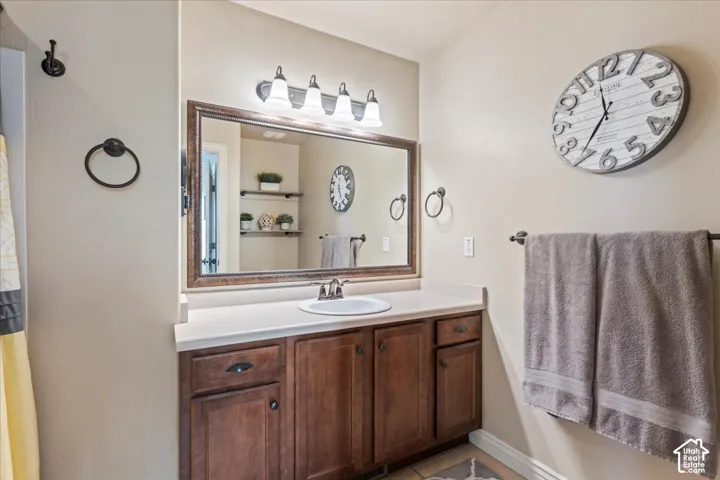 Wood-finish vanity with a single basin sink, light-toned countertop, and an ornate framed mirror