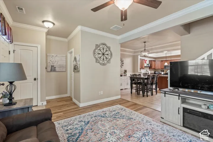 Wood-finish flooring throughout, crown molding detailing, and a ceiling fan with integrated lighting