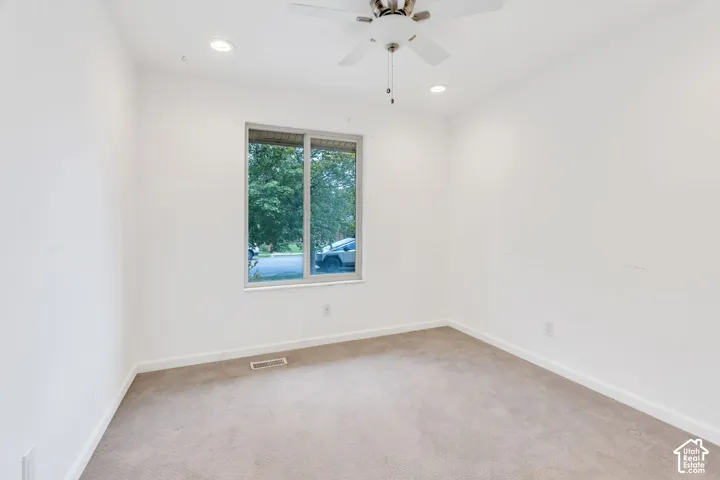 Recessed lighting, ceiling fan, neutral wall color, carpet flooring, and a large window
