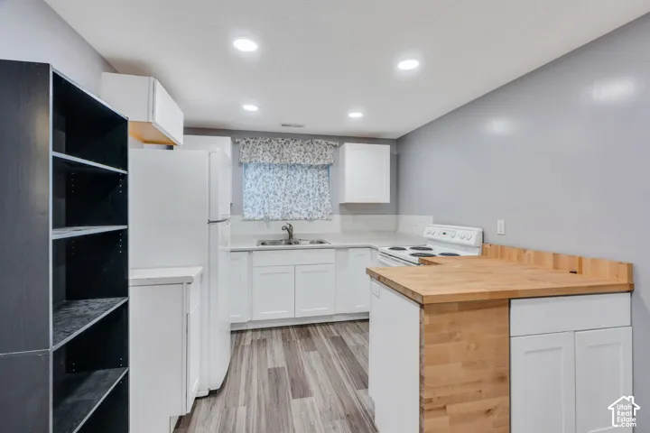 Kitchen featuring white cabinetry, light-toned countertops, wood-finish flooring, and recessed lighting