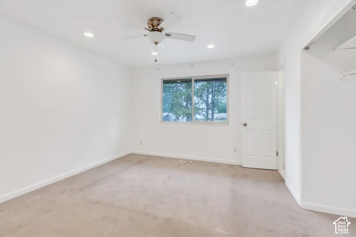 Recessed lighting, ceiling fan, white paneled door, sliding window, and carpeted flooring