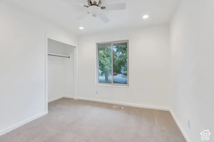 Neutral tone wall paint, recessed lighting, ceiling fan, carpeting, and a window
