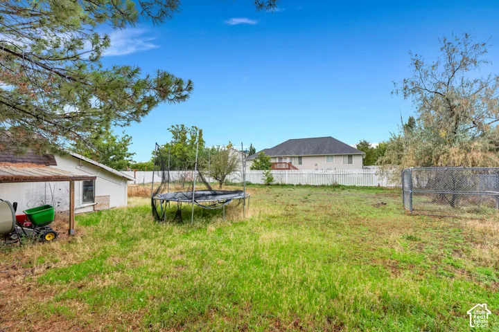 Expansive grassy yard with a white picket fence backdrop and established trees
