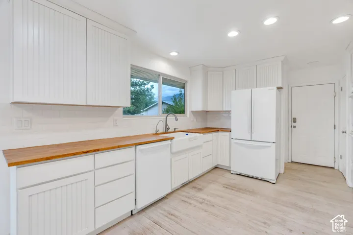 White shaker cabinetry, wood-finish countertops, subway tile backsplash, farmhouse-style sink, and recessed lighting