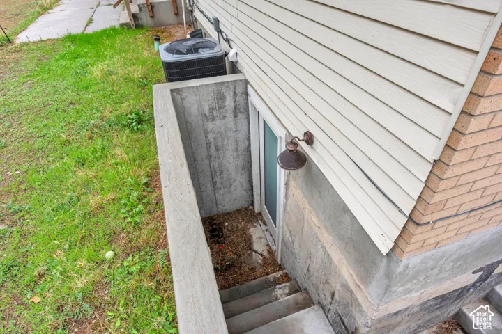Concrete basement access with exterior lighting and brick-finish siding