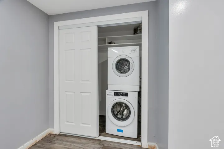 Laundry closet featuring a stacked washer and dryer, white paneled bifold doors, and built-in shelving