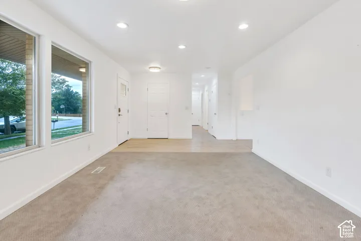 Recessed lighting, wood-finish flooring, white paneled doors, and large picture windows