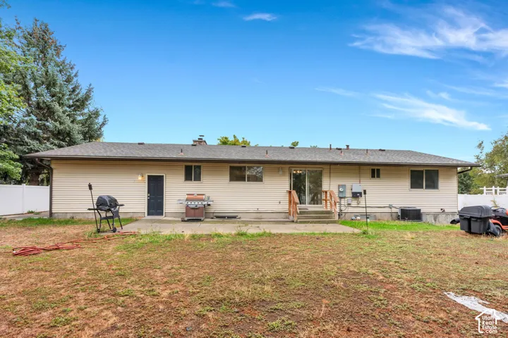 Rear exterior with tan horizontal siding, a concrete patio, and a sliding glass door