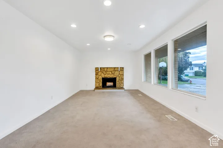 Spacious interior with neutral carpeting, stone-clad fireplace, and multiple large windows