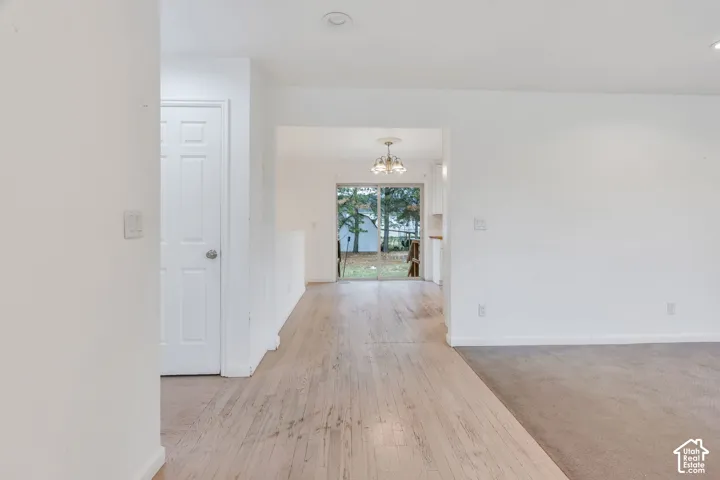 Light wood-finish flooring extending into the background, white interior doors with satin nickel hardware, recessed ceiling lighting, and a glass sliding door