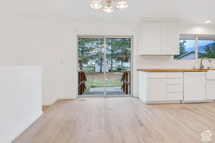 Wood-finish flooring with white kitchen cabinetry, wood countertops, and a farmhouse sink
