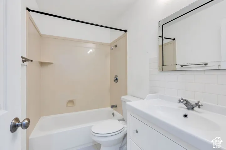 Bathroom featuring a built-in tub with a shower, a vanity with an integrated sink, and subway tile backsplash