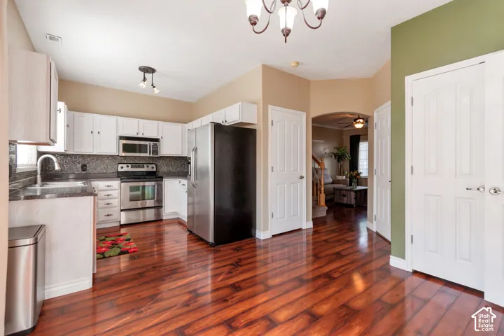Kitchen featuring wood-finish flooring, white cabinetry, dark countertops, and stainless steel appliances