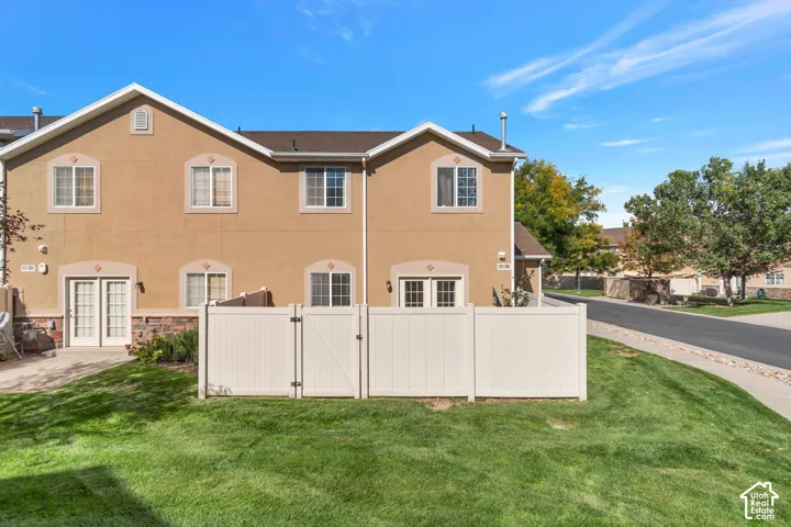 Stucco exterior with stone accent, white vinyl fencing, and a manicured lawn