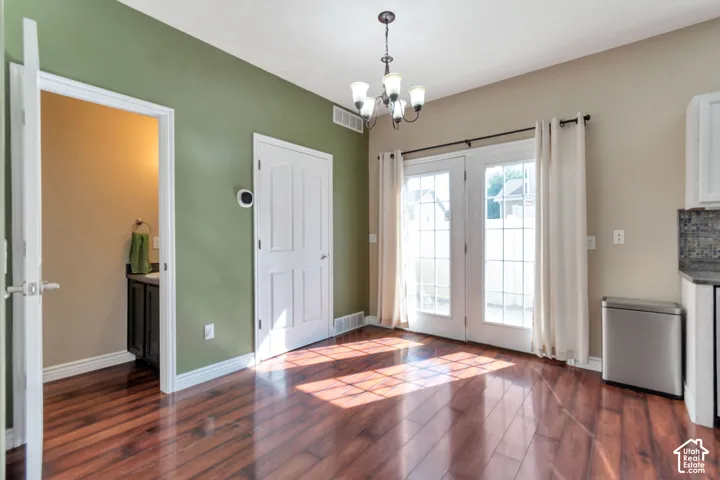 Wood-finish flooring with a multi-tone wall design, glass French doors, and an attached chandelier