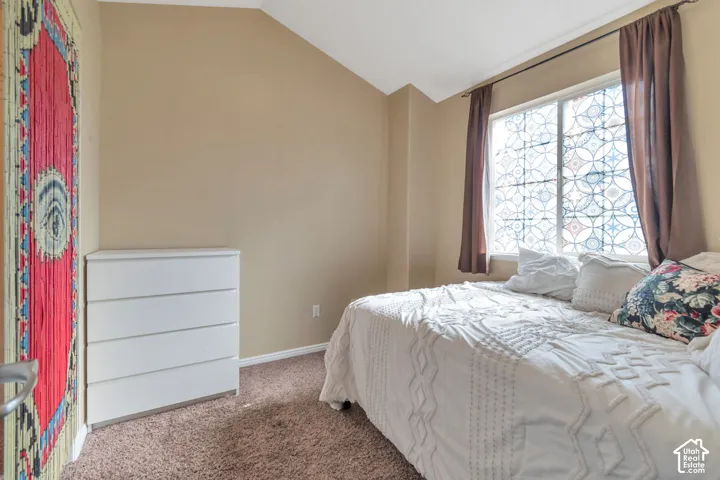Vaulted ceiling, neutral wall tones, window with decorative privacy film, and wall-to-wall carpeting