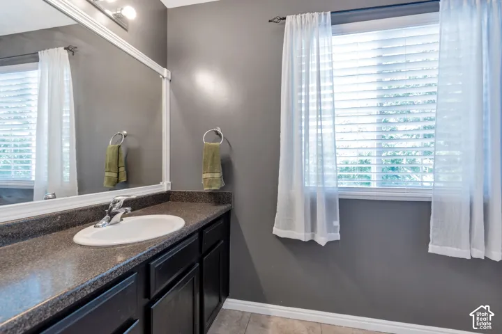 Vanity with an oval undermount sink, dual-handle faucet, and dark-toned countertop