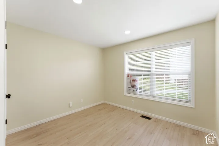 Recessed lighting, light wood-finish flooring, white trim, and a large window with white blinds