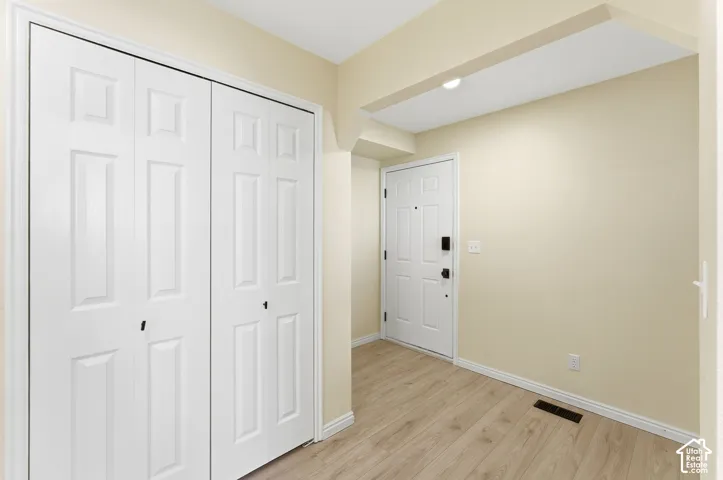Entryway featuring wood-finish flooring, a paneled entry door with dark hardware, and bi-fold closet doors