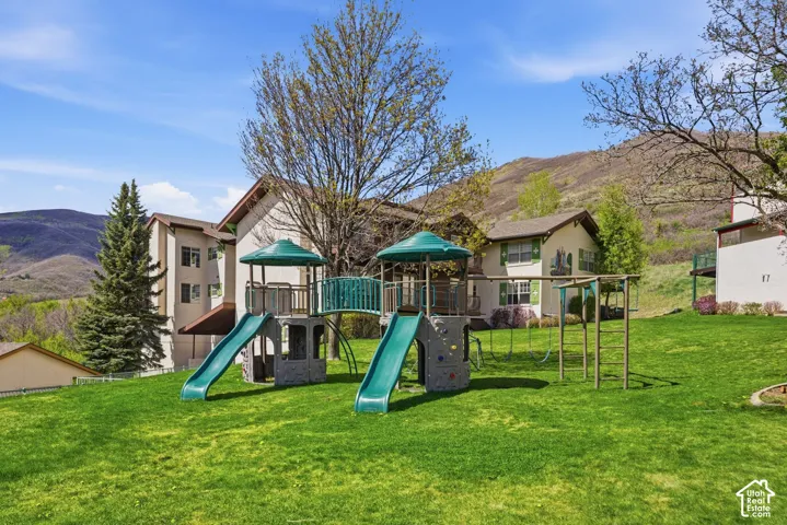 Expansive lawn featuring a multi-level play structure with slides and swings
