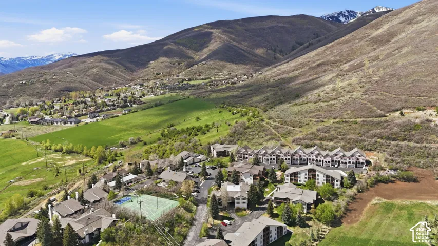 Community featuring a tennis court, multiple residential buildings, and surrounding natural landscapes with mountains