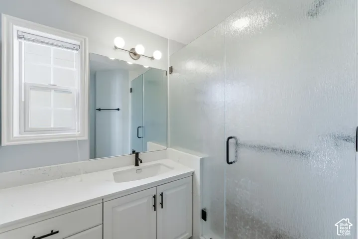 White vanity with a rectangular undermount sink, a matte black faucet, and a quartz-finish countertop