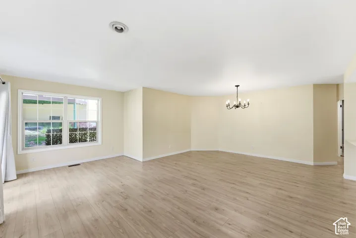 Spacious interior with wood-finish flooring, a contemporary chandelier, recessed lighting, and a large window