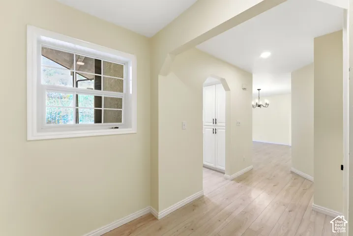 Light-toned wood-finish flooring throughout, white trim, arched doorway, recessed lighting, and white built-in cabinetry